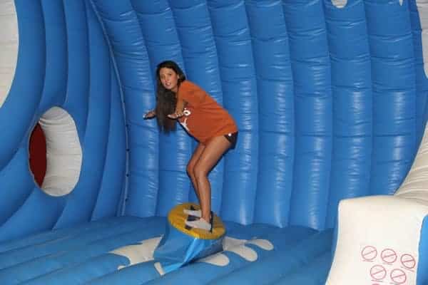 Texas girl balancing on surfboard simulator - Party Game Rental